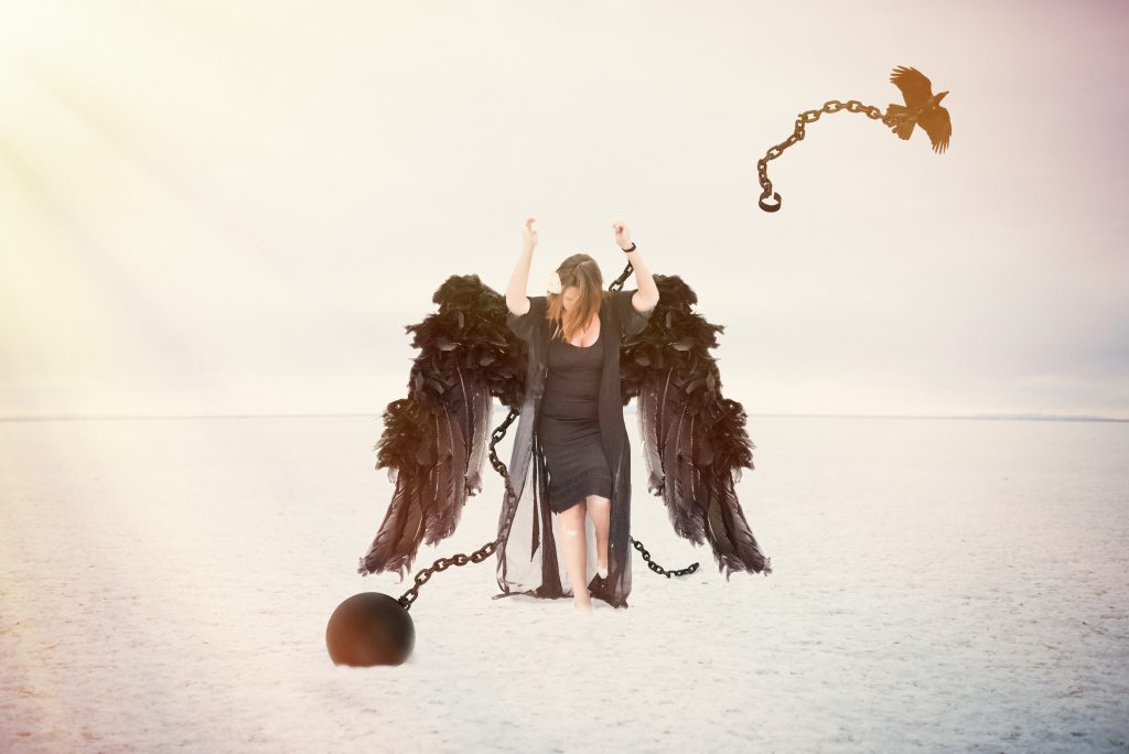 woman in vast desolate salt flats using smartphone to take selfies - raven takes away her chains
